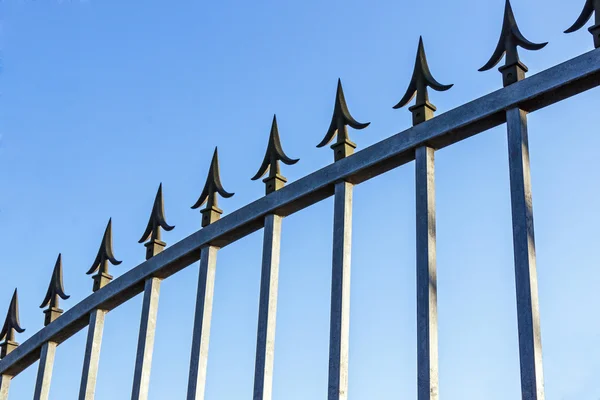 Kolce na brama ocynkowana przeciw błękitne niebo — Zdjęcie stockowe