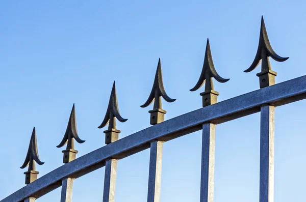 Spikes no portão galvanizado contra o céu azul — Fotografia de Stock