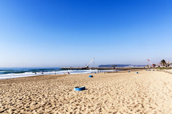 Praia com lixeiras azuis e guindastes no cais — Fotografia de Stock