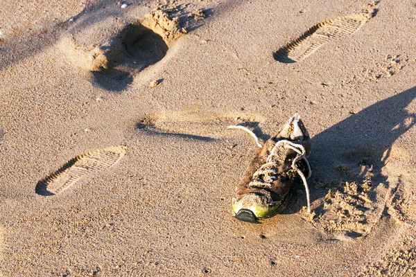 Alte verlassene nasse schmutzige Schuhe auf Sand am Strand — Stockfoto