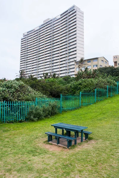 Green Picnic Table Grassy Slope Tall Residential Building — Stock Photo, Image