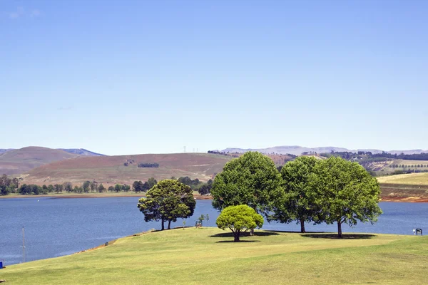 Area picnic coperta di alberi sulle rive della diga — Foto Stock