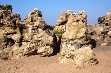 Plajda mavi gökyüzü karşı yıpranmış kaya oluşumları