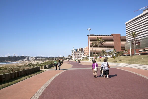 Peatones caminando a lo largo del paseo pavimentado en frente de la playa —  Fotos de Stock