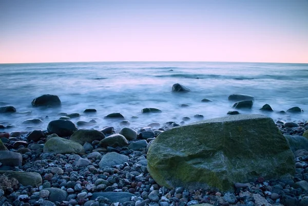 Romantis pagi di laut. Batu-batu besar mencuat dari permukaan air yang halus. Pink horozon dengan sinar matahari panas pertama . — Stok Foto