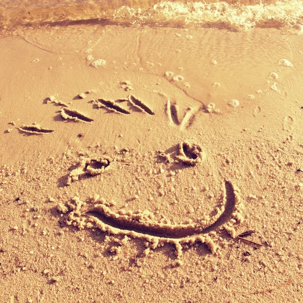 Смешная улыбка на мокром песке у моря — стоковое фото