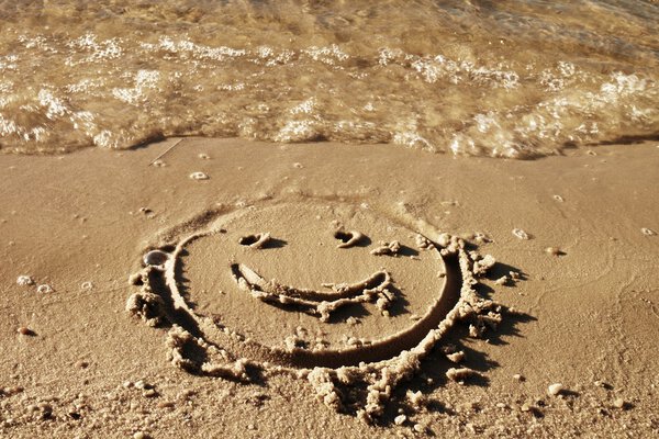 Funny smile face drawn on wet sand near sea