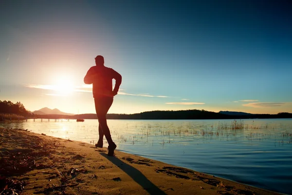 Αθλητής τρέχει στο καταπληκτικό ηλιοβασίλεμα καλοκαίρι κατά μήκος της ακτής στο άθλημα και υγιούς τρόπου ζωής — Φωτογραφία Αρχείου