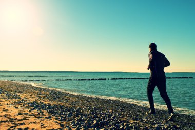 Adam siyah Çalıştır ve egzersiz dalgakıran, sahilde.