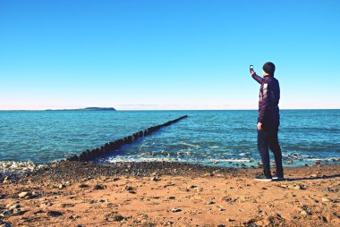 Siluet spor aktif yetişkin adam çalıştıran ve sahilde egzersiz. Sakin su, ada ve günbatımı gökyüzü arka plan.
