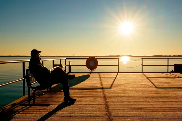 Silueta de deporte activo hombre adulto corriendo y haciendo ejercicio en la playa. Calma agua, isla y puesta del sol cielo fondo . — Foto de Stock