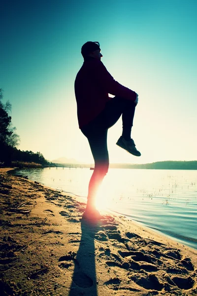 Silhouette di sport attivo uomo adulto in esecuzione ed esercizio sulla spiaggia. Acqua calma, isola e tramonto cielo sfondo . — Foto Stock