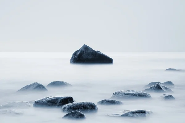 Kayalık sahilleri deniz, günbatımında. Yumuşak su seviyesi ve rüya gibi etkisi düşük çekim hızı