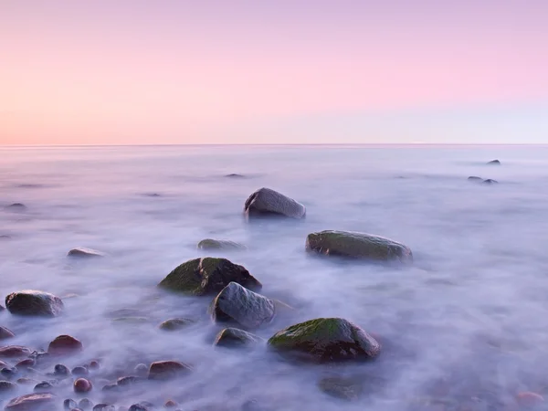 Puesta de sol en la costa rocosa del mar. Baja velocidad de obturación para un nivel de agua suave y efecto de ensueño — Foto de Stock