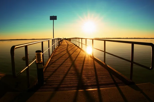 Morning in harbor. Tourists walk on pier above sea. Clear blue sky, smooth water level Royalty Free Stock Photos