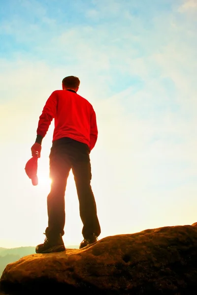 Wanderer in rotem Sweatshirt mit roter Mütze auf dem Gipfel des Felsens, der über das Tal zur Sonne wacht. schöner Moment — Stockfoto