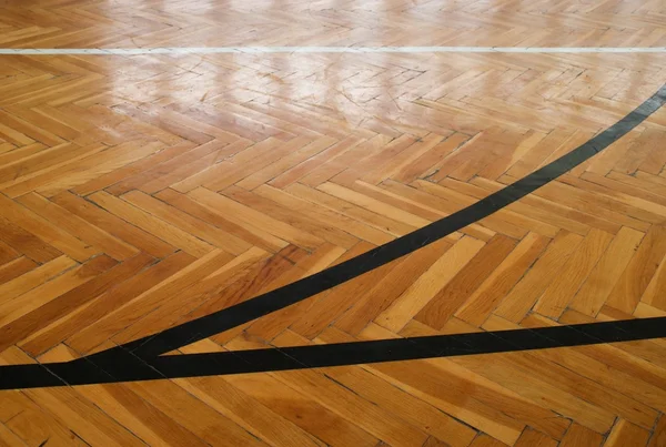 Schwarze Linien in der Halle. Abgenutzter Holzboden der Sporthalle mit bunten Markierungslinien — Stockfoto