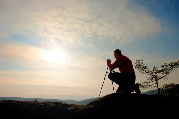 Naturfotograf mit Stativ auf Klippe und Denken. verträumtes Nebeltal unten — Stockfoto