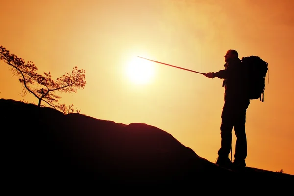 Reiseführer zeigen den richtigen Weg mit der Stange in der Hand. Wanderer mit sportlichem Rucksack stehen auf felsigem Aussichtspunkt über nebligem Tal. — Stockfoto