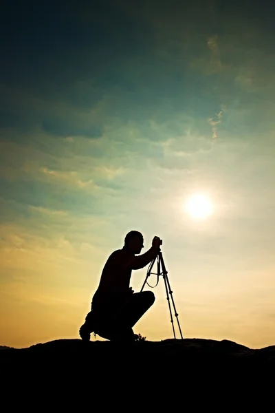 Fotógrafo de natureza com tripé em penhasco e pensamento. Paisagem nebulosa sonhadora, nebuloso nascer do sol no vale abaixo — Fotografia de Stock
