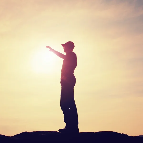 Turista en gorra de béisbol roja tocando a Sun. Caminante de pie en el pico de roca arenisca en el parque nacional — Foto de Stock