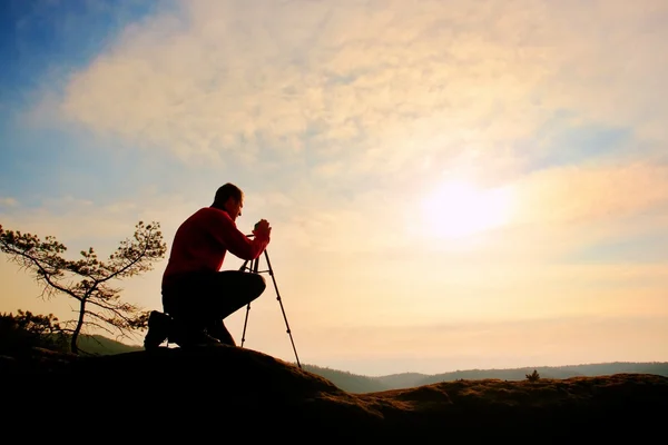 Naturfotograf mit Stativ auf Klippe und Denken. verträumtes Nebeltal unten — Stockfoto