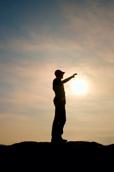 游客在触摸到太阳的徒步旅行者站在国家公园的砂岩岩峰上的红色棒球帽 — 图库照片