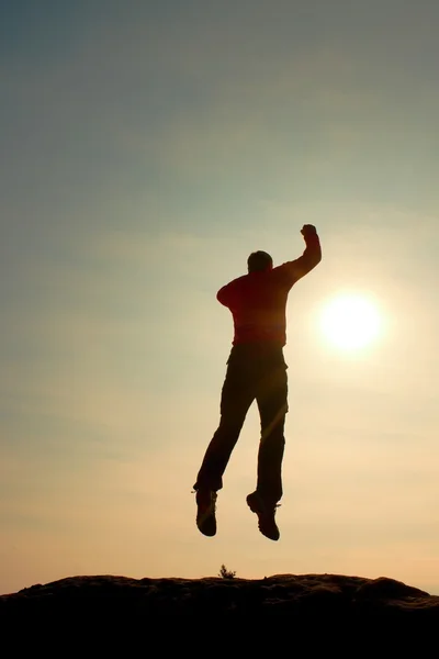 Saltando hombre. Joven loco está saltando en el fondo del cielo colorido.Silhouette de hombre saltando y hermoso cielo puesta de sol . — Foto de Stock