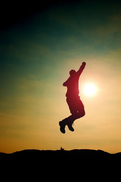 Jumping man. Young crazy  man is jumping on colorful sky background.Silhouette of jumping man and beautiful sunset sky. — Stock Photo, Image