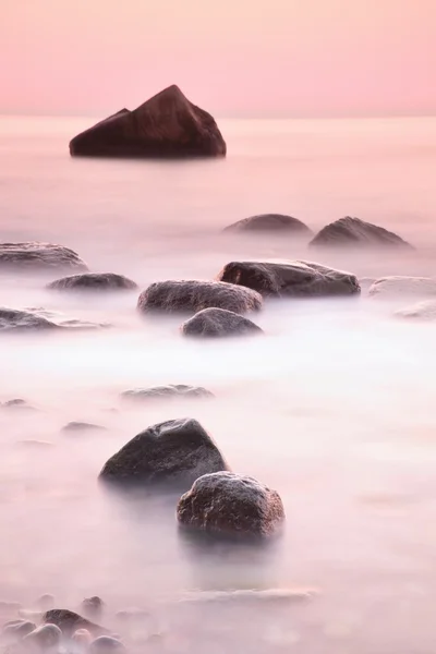 Romantic morning at sea. Big boulders sticking out from smooth wavy sea. Long exposure — Stock Photo, Image