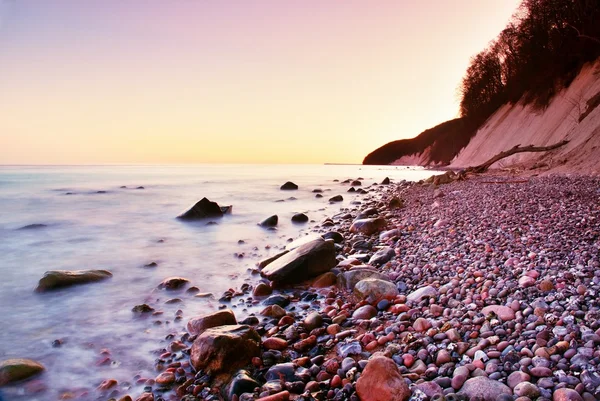 Голубое море и небо, волны разбивают каменный берег. Момент перед восходом солнца — стоковое фото