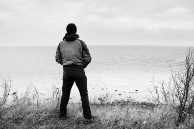 Windcheater adam cliff bay ve deniz kadar ufuktan looki yukarıda durmak. Rüzgarlı soğuk hava