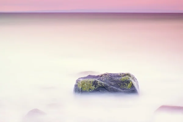 Romantickou atmosféru v klidné dopoledne na moři. Velké balvany vyčnívající z hladké vlnité moře. Růžový obzor — Stock fotografie
