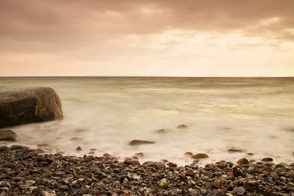Ambiente romántico en la mañana tranquila en el mar. Grandes rocas que sobresalen del suave mar ondulado. Horizonte rosa — Foto de Stock