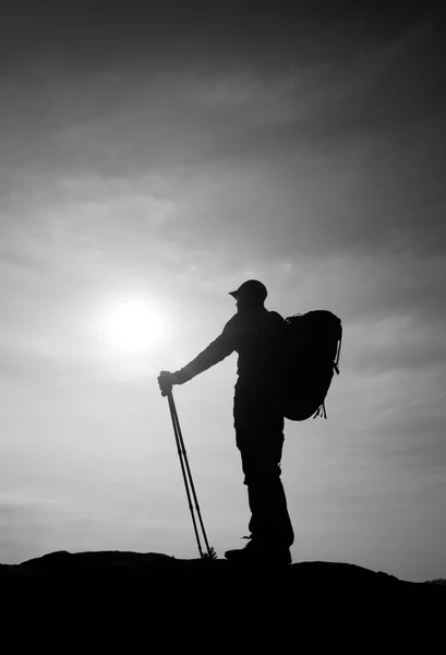 Турист у вітрогенераторі зі спортивними стовпами в руках стоїть на скелястій точці зору . — стокове фото