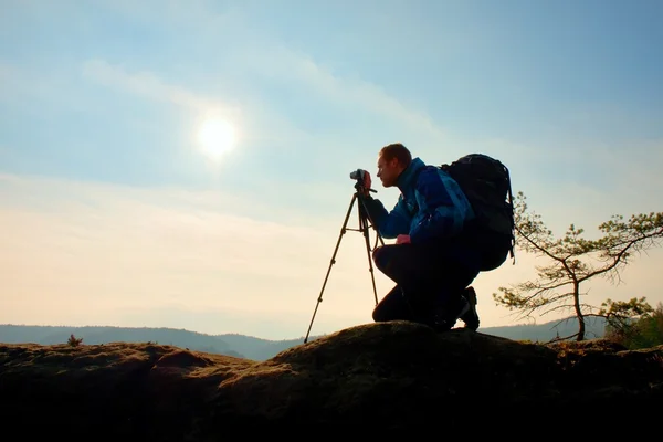 アマチュア写真家は、岩のピークでミラー カメラで写真をとります。夢のような濃霧発生風景、春オレンジ ピンクの霧日の出 — ストック写真