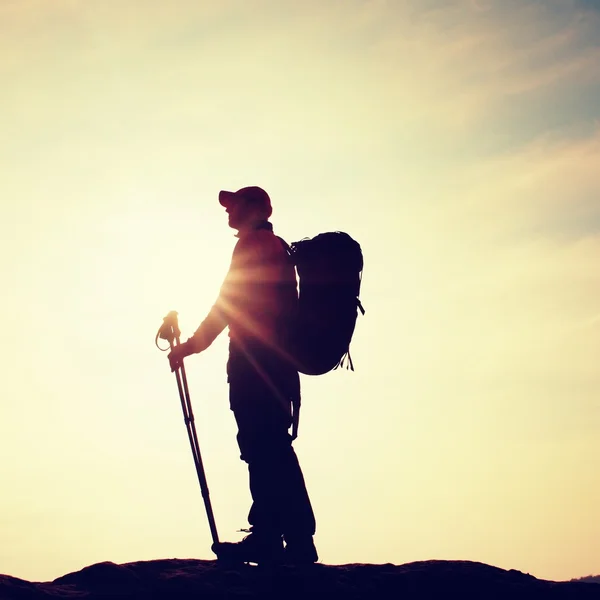 Turista in giacca a vento con bastoncini sportivi in mano stare sul punto di vista roccioso . Foto Stock Royalty Free