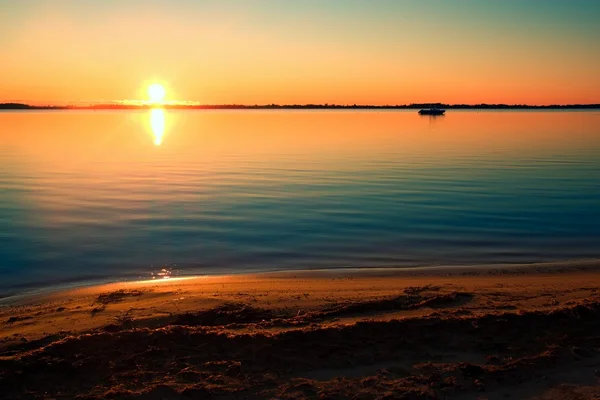 Nível do lago liso no pôr do sol colorido quente, praia de areia — Fotografia de Stock