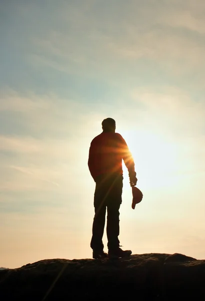 Wanderer in rotem Sweatshirt mit roter Mütze auf felsigem Gipfel. Mann wacht über Tal zur Sonne. schöner Moment das Wunder der Natur. — Stockfoto