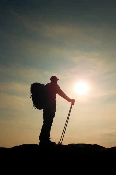 Турист у вітрогенераторі зі спортивними стовпами в руках стоїть на скелястій точці зору . — стокове фото