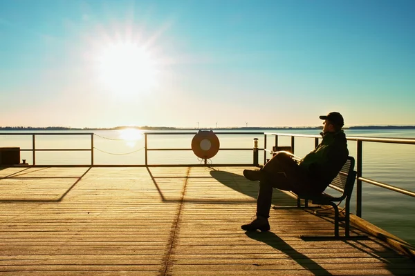 남자는 부두에 앉아서 아침 바다에서 즐길 수 있습니다. 써니 맑고 푸른 하늘, 부드러운 물 수준 — 스톡 사진