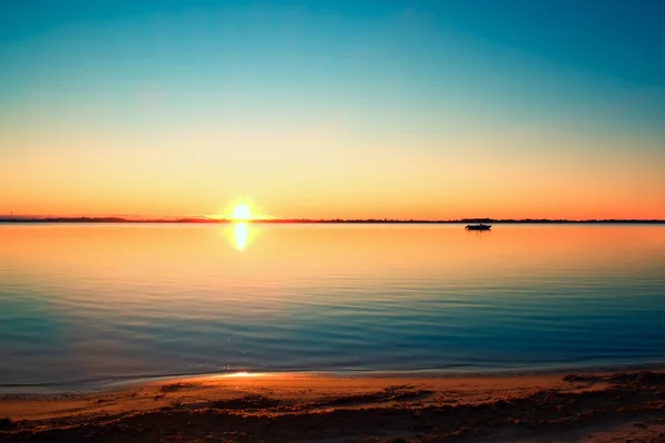 Sima tó szintű színes meleg naplemente, homokos strandon — Stock Fotó