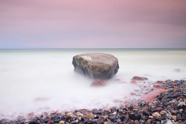 Ρομαντική ατμόσφαιρα σε ήσυχη το πρωί στη θάλασσα. Μεγάλες πέτρες να κολλήσει έξω από την ομαλή, κυματιστό θάλασσα. Ροζ ορίζοντα — Φωτογραφία Αρχείου