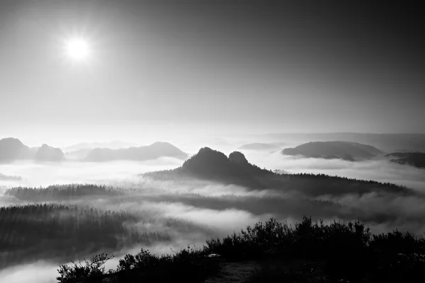 Fantastic sunrise on the top of the rocky mountain with view into misty valley. Black and white — Stock Photo, Image