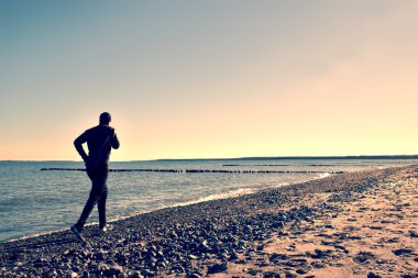 Adam siyah Çalıştır ve egzersiz dalgakıran, sahilde.