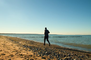 Uzun boylu adam çalıştıran ve dalgakıran, taşlı plajda egzersiz karanlık sportswer.