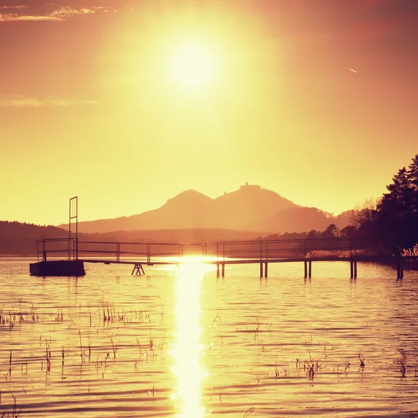 Farbenfroher Herbstsonnenaufgang an der Küste, verlassener Anleger. Insel mit Festung am Horizont. — Stockfoto