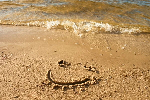 Смешная улыбка на мокром песке у моря — стоковое фото