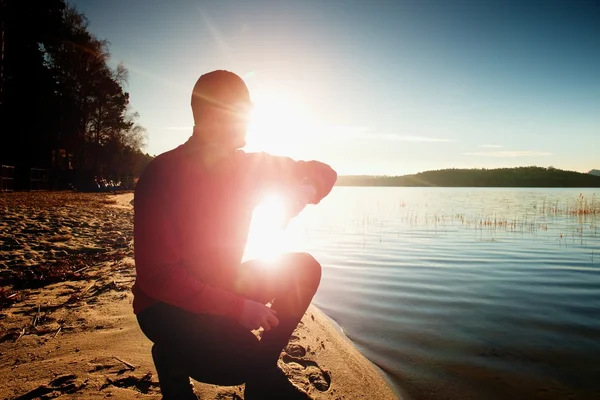 Man athlete checking time during workout run exercise outdoors at ocean beach in sunny cold morning — Stock Photo, Image