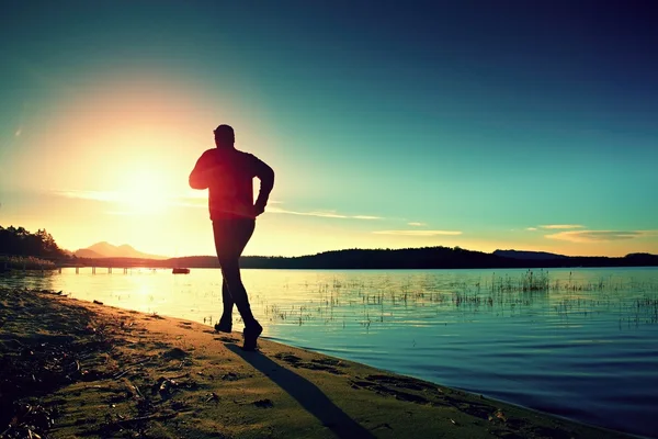 Esportista correndo no incrível pôr do sol de verão ao longo da costa no esporte e estilo de vida saudável — Fotografia de Stock